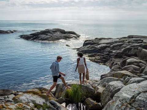Et kjærestepar går langs skjærgården på sørlandet.