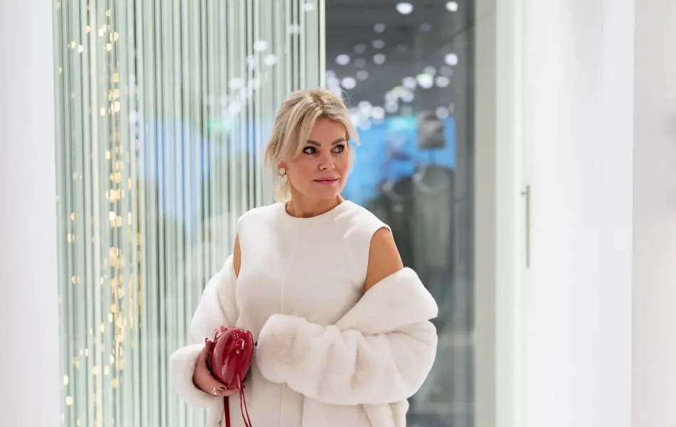 Dame med hvit kåpe, hvit kjole, rød veske, røde pumps, sorte nylonstrømer