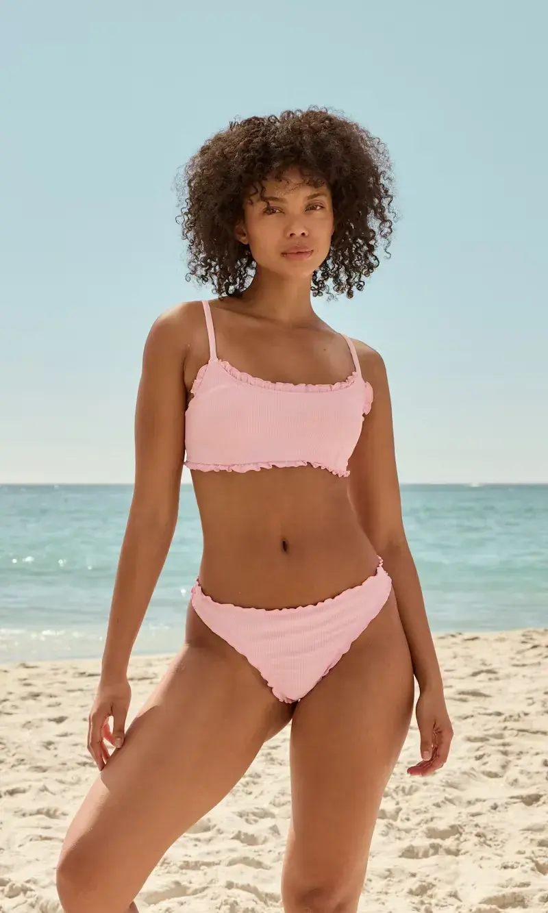 Jente på strand i rosa bikini