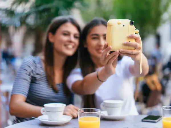 To jenter tar selfie med polaroidkamera