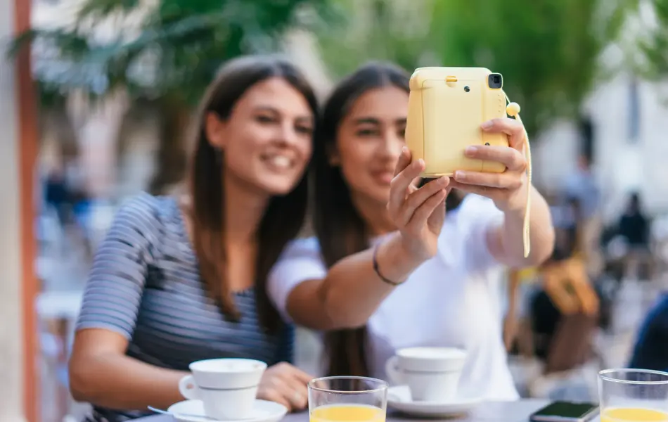 To jenter tar selfie med polaroidkamera