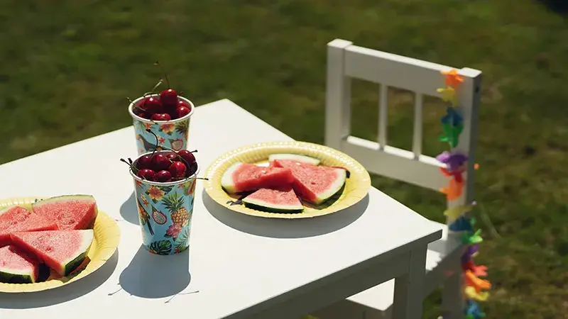 Barne-bord dekket til sommerfest med sommertallerken, melon og kirsebær