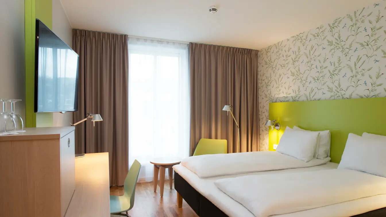 Dobbeltseng med blomstertapet, tv og skrivepult på double room på Thon Hotel Sandven i Nordheimsund