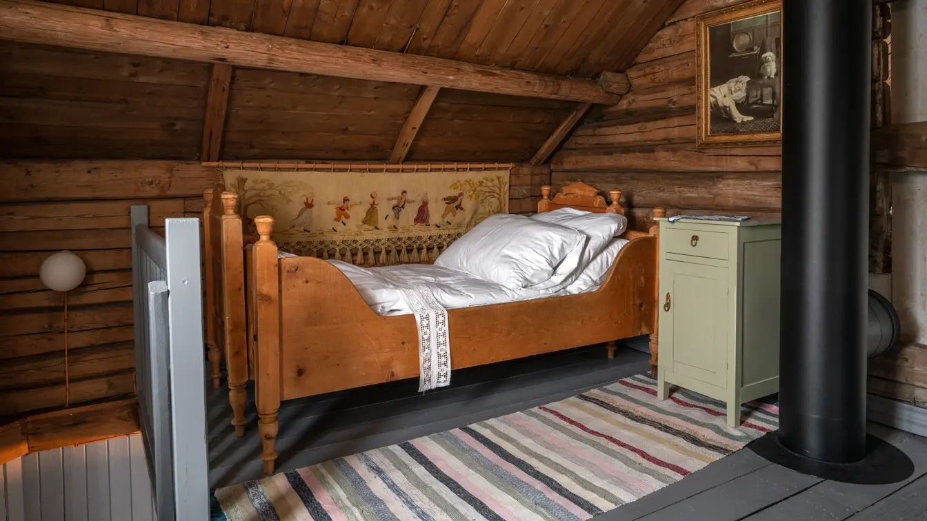 En av sengene på utsiden av soverommet, med tilhørende nattbord.