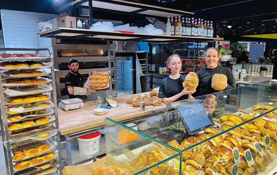 Tre som holder opp bakevarer bak disken