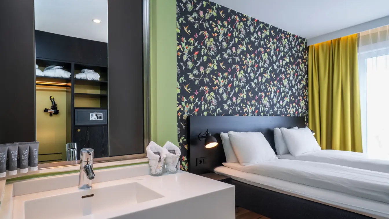Vask, dobbeltseng og blomstrete tapet i business rom på Thon Hotel Gyldenløve i Oslo