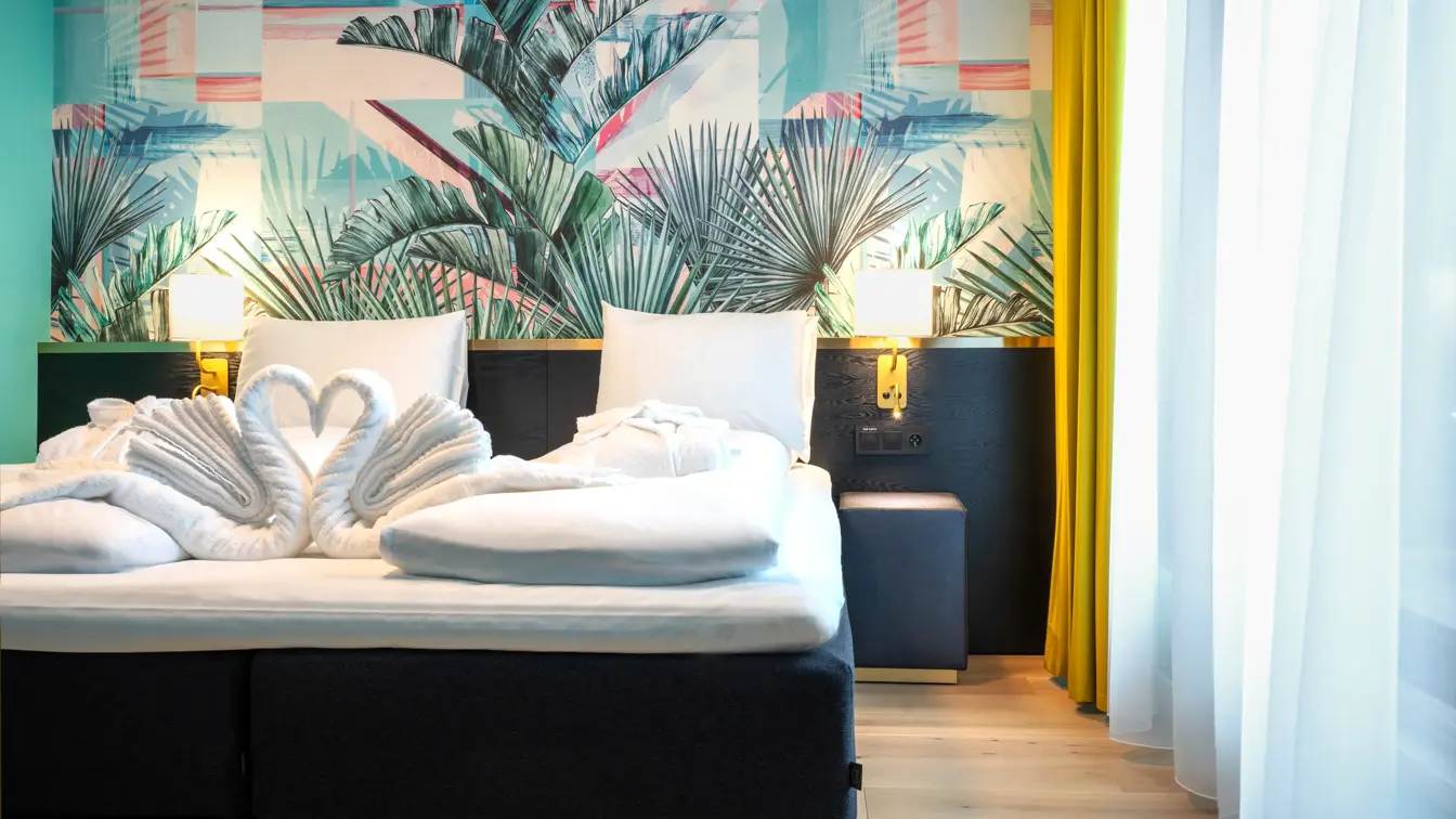 Dobbeltseng med tapet med jungelblader på suite på Thon Hotel Storo i Oslo