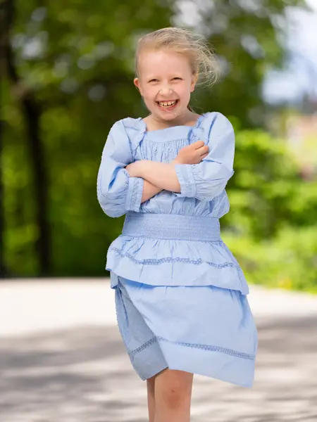 Jente står ute i lyseblå kjole