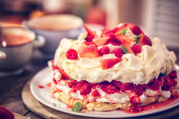 Delicious Berry Pavlova Cake with fresh strawberries, raspberries, mint leaves and whipped cream.