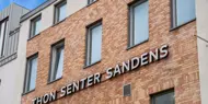 Thon Senter Sandens fasade, med logo skilt på veggen.