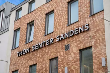 Thon Senter Sandens fasade, med logo skilt på veggen.
