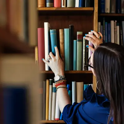 Dame leter etter bok i bokhylle