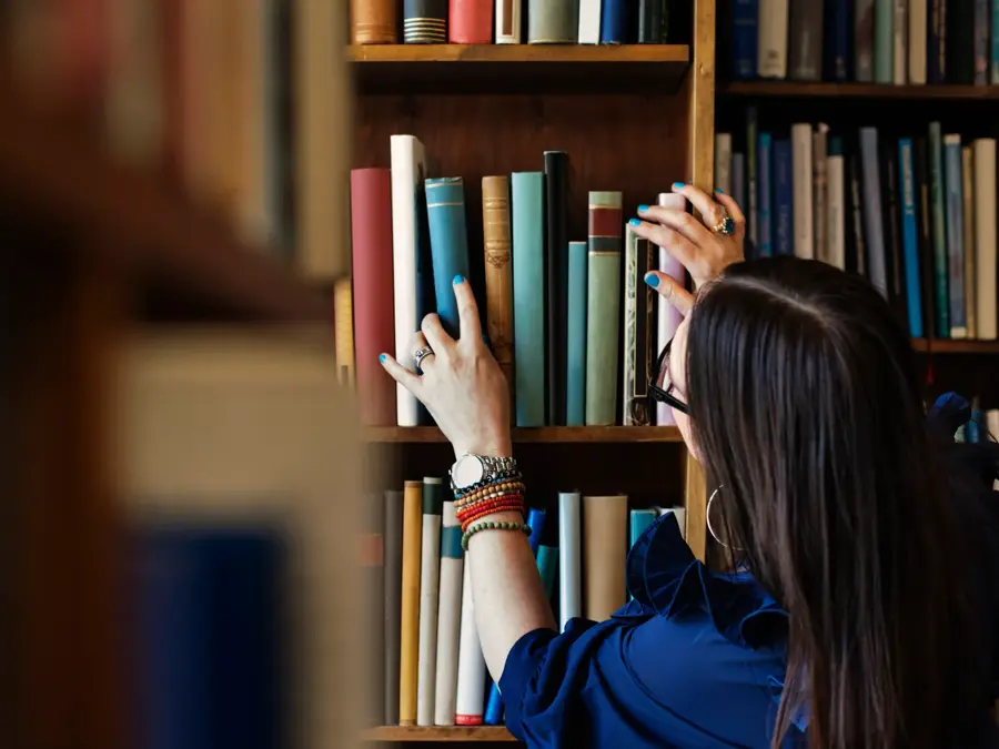 Dame leter etter bok i bokhylle