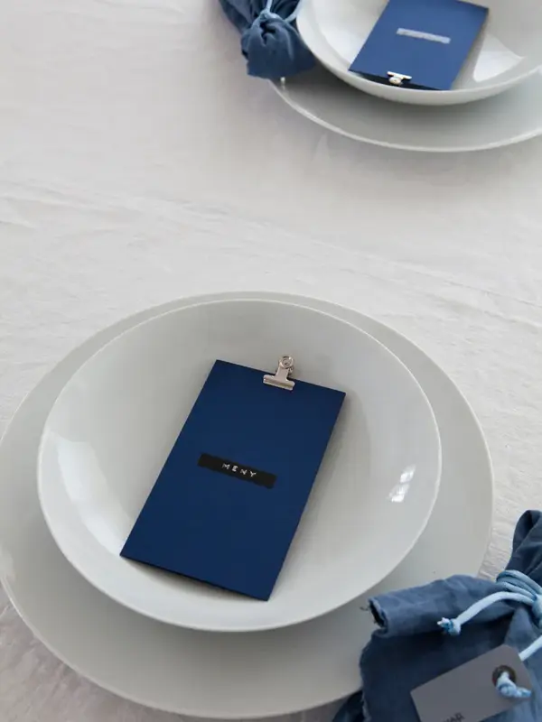 Steg 3 - Bord dekket med mørkeblå tøyservietter og blått menykort