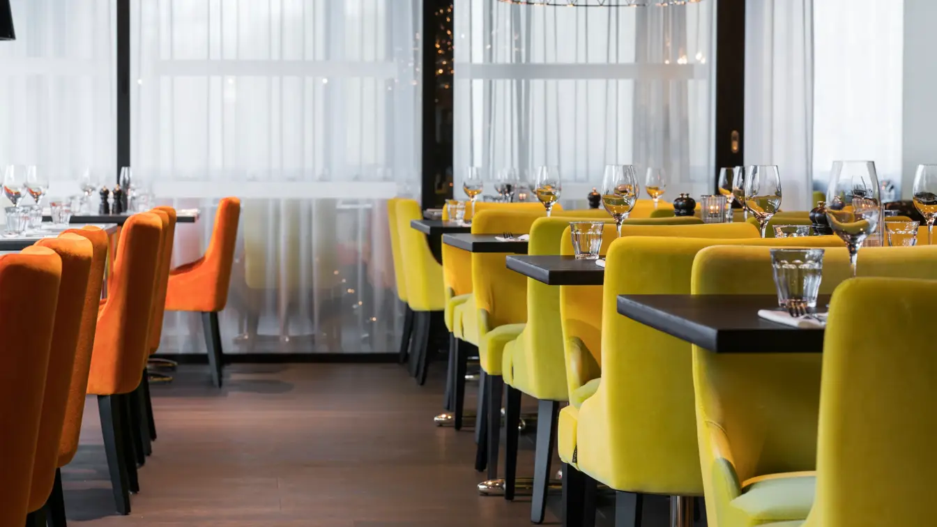 Frokostsal med gule og orange stoler ved dekket bord på Thon Hotel Oslo Airport ved Gardermoen
