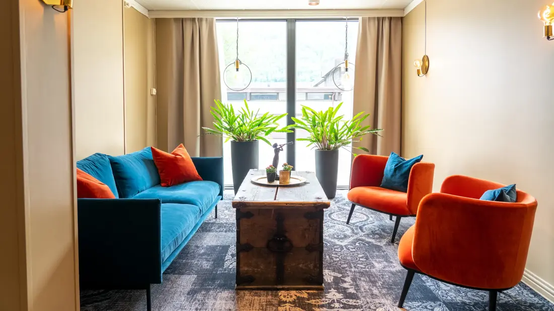 Vindu, blå sofa, røde lenestoler, salongbord, planter