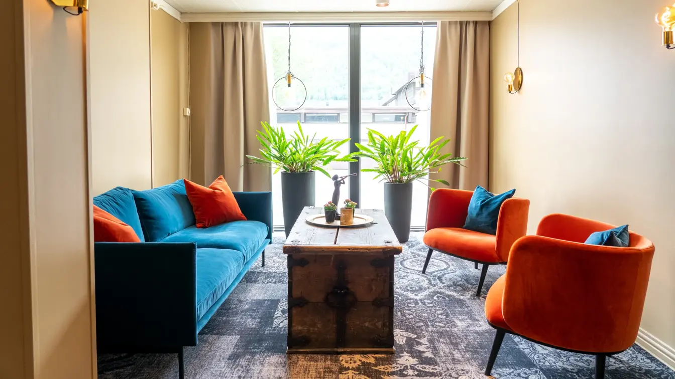 Vindu, blå sofa, røde lenestoler, salongbord, planter