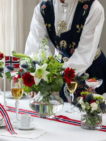 Dame som setter en vase med blomster på et tildekket bord