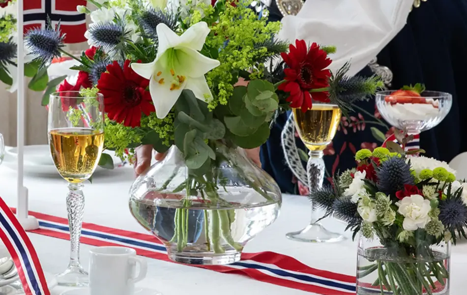 Dame som setter en vase med blomster på et tildekket bord