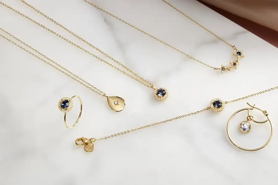 Forgylte gullsmykker som ligger på en marmor plate. 