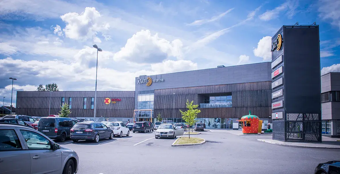 Fasadebilde av AMFI Eidsvoll med biler parkert ved inngangen