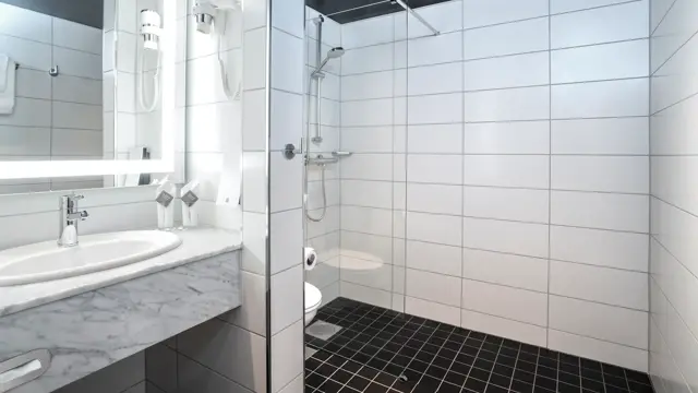 To enkeltsenger, blomstret tapet bak sengene, gul stol, arbeidspult og store vinduer med store gule gardiner på twin room på Thon Hotel Cecil i Oslo sentrum