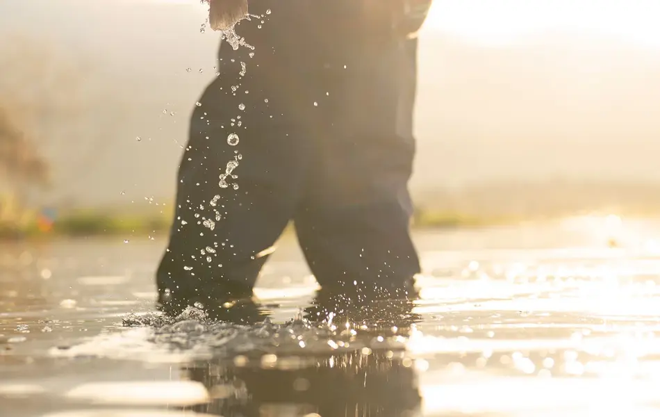 Omriss av mann som fisker og drar opp en fisk i solnedgang. Foto til artikkel om julekalendertips til mann.