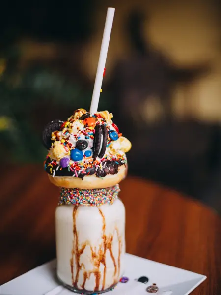 Mexico, Queretaro, Queretaro - April 4, 2018: Chocolate donut milkshake with lots of toppings, sprinkles, popcorn, cookies and cream standing on a wooden table