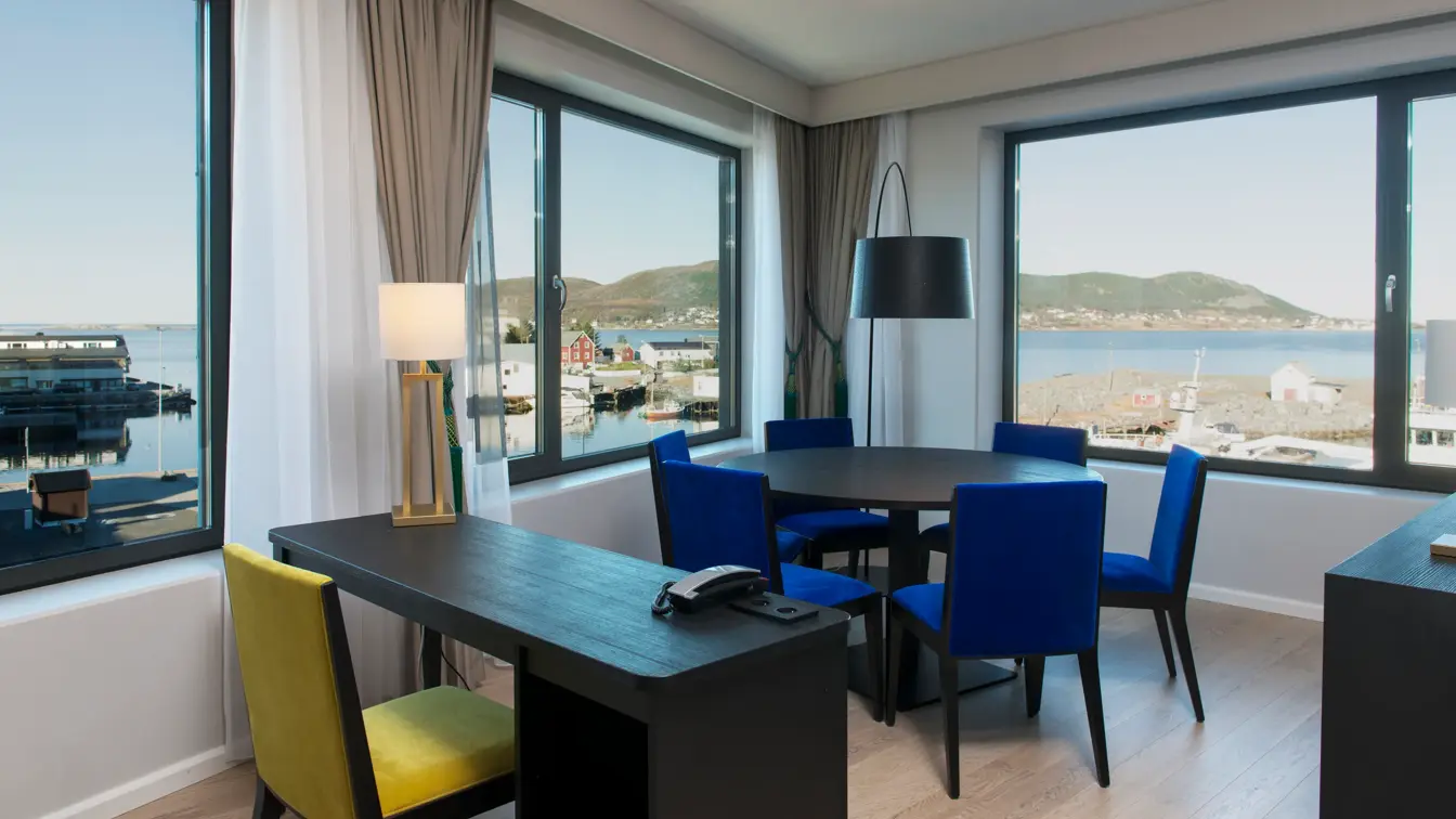 Sittegruppe med bord, samt arbeidspult på Dobbelseng og stol i suite på Thon Hotel Fosnavåg med utsikt utover havet