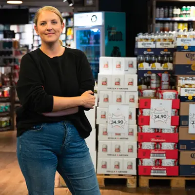 Dame som smiler til kamera med butikk i bakgrunn