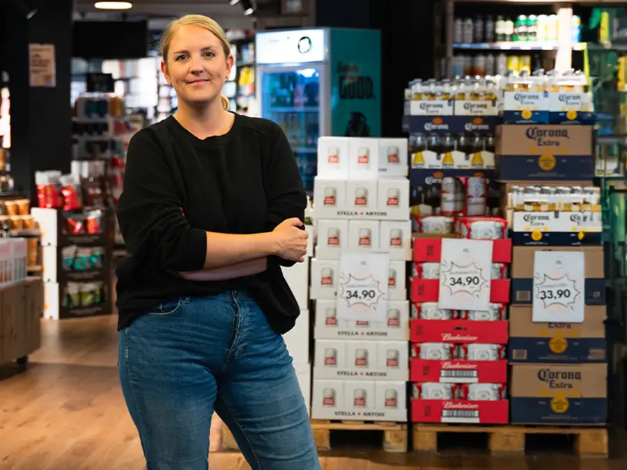 Dame som smiler til kamera med butikk i bakgrunn