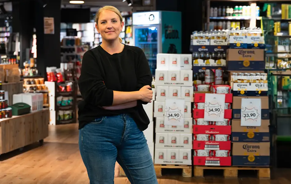 Dame som smiler til kamera med butikk i bakgrunn