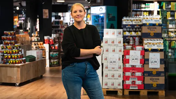 Dame som smiler til kamera med butikk i bakgrunn