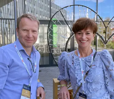 Ole Sørlie og Gro Collett står foran et bygg med glassfasade og smiler til kamera.