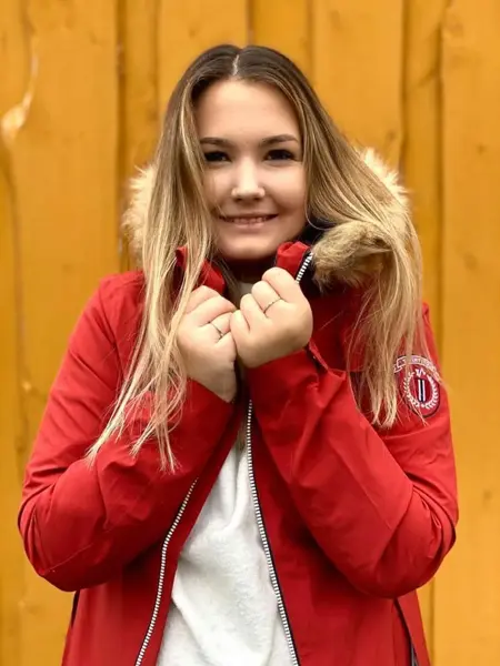 Ung kvinne med rød jakke foran gul bakgrunn