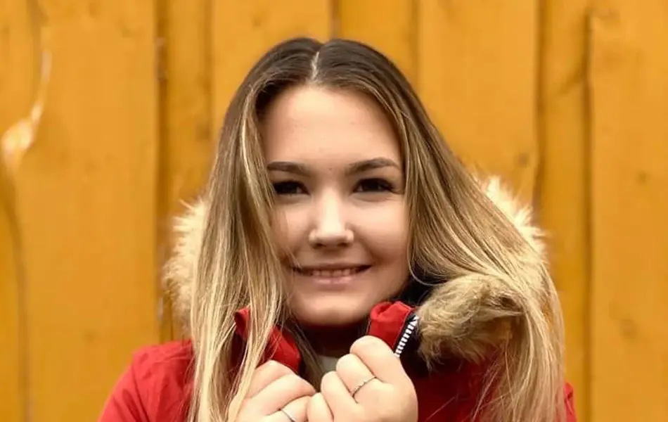 Ung kvinne med rød jakke foran gul bakgrunn