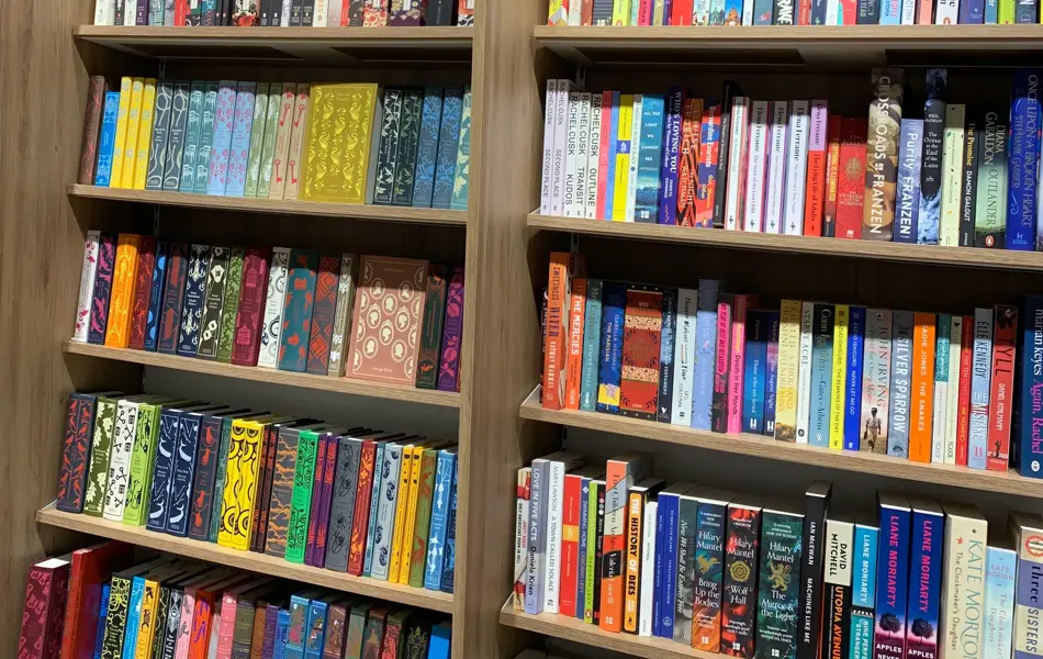 Norli med eikebokhyller fra gulv til tak fylt med bøker i ulike sjangre