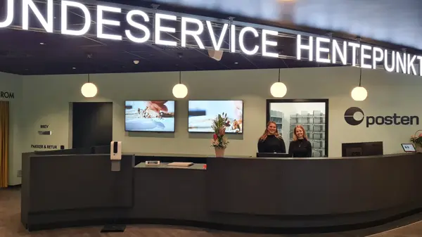 to damer står bak disken til kundeservice, hentepunkt og posten
