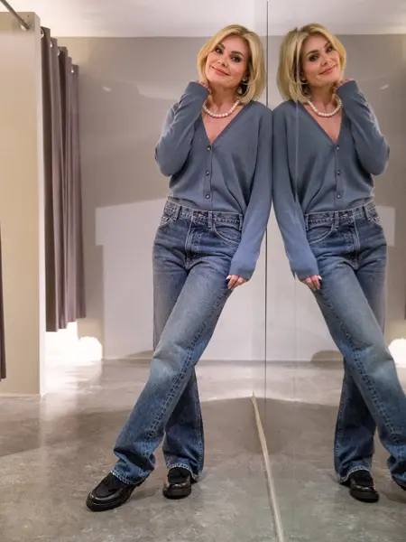 Dame i dueblå cardigan, jeans og sorte sko