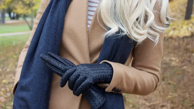 Dame har på seg kåpe og har tatt av seg en hanske