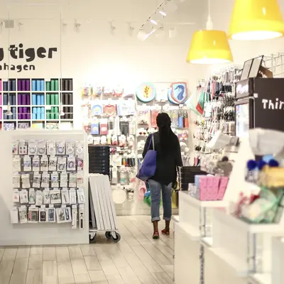 En dame med veske som går gjennom butikken til Flying Tiger Copenhagen