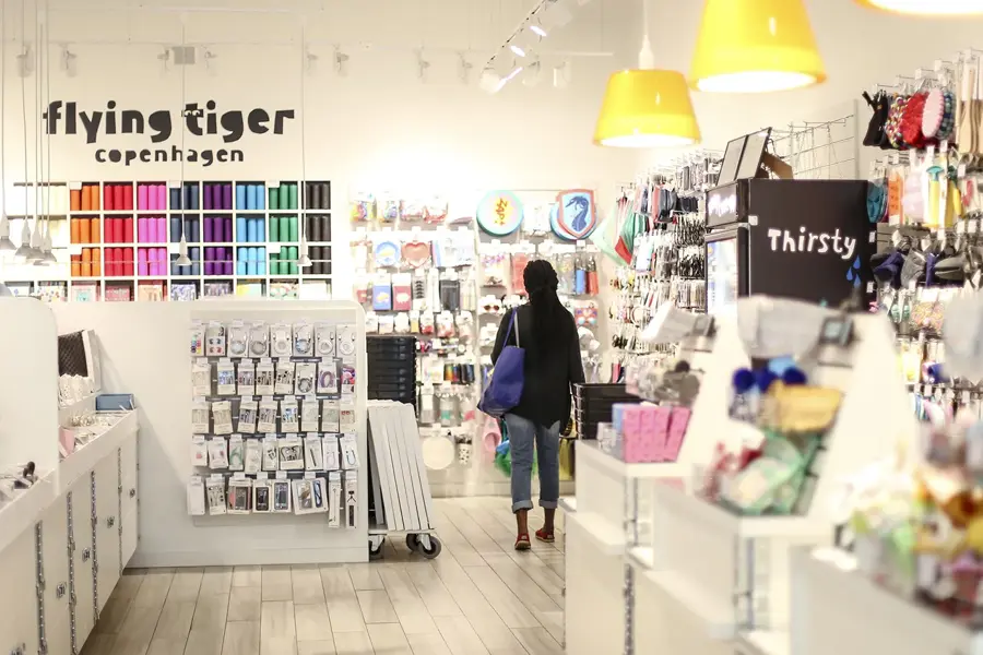 En dame med veske som går gjennom butikken til Flying Tiger Copenhagen