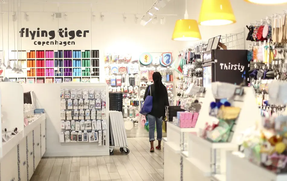 En dame med veske som går gjennom butikken til Flying Tiger Copenhagen