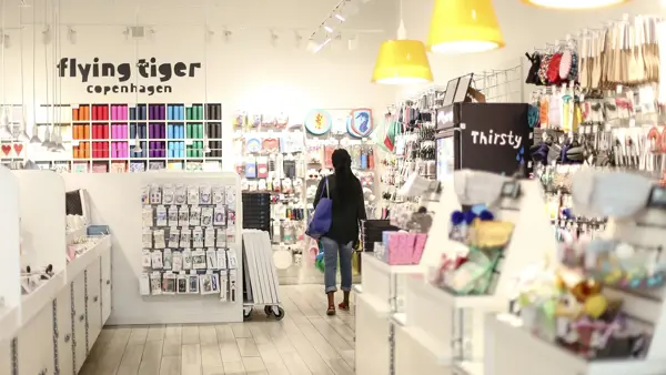 En dame med veske som går gjennom butikken til Flying Tiger Copenhagen