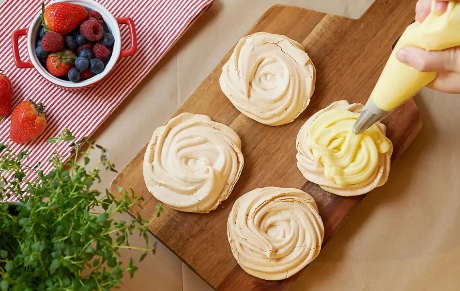 Noen som sprøyter vaniljekrem på marengs