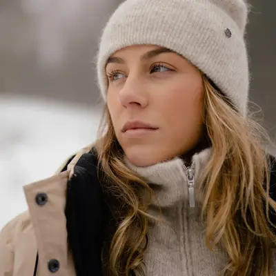 Dame som poserer med beige lue, genser med glidelås og vinterjakke