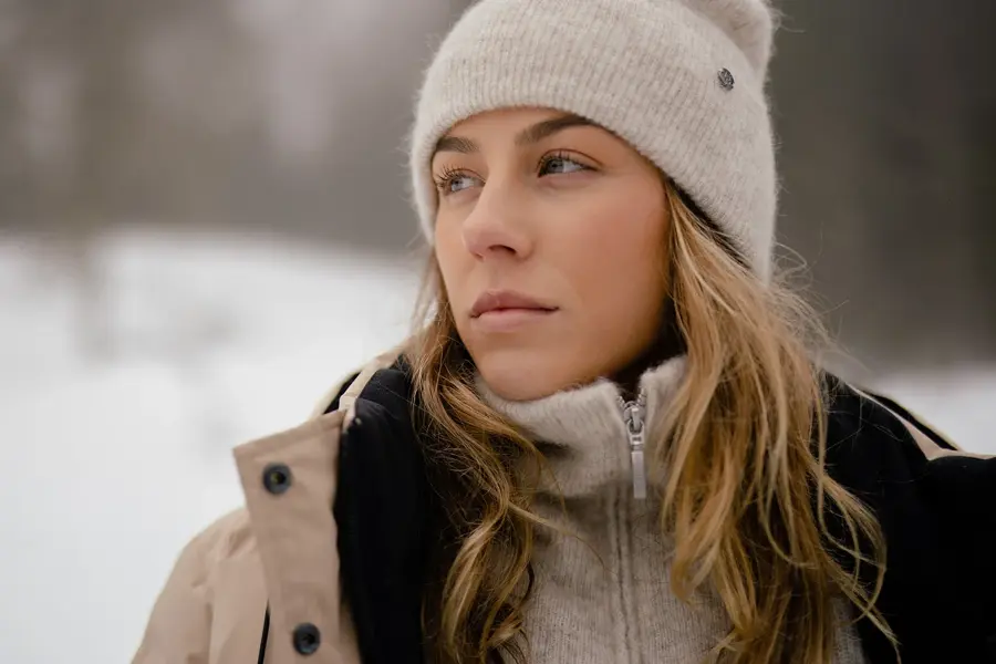 Dame som poserer med beige lue, genser med glidelås og vinterjakke