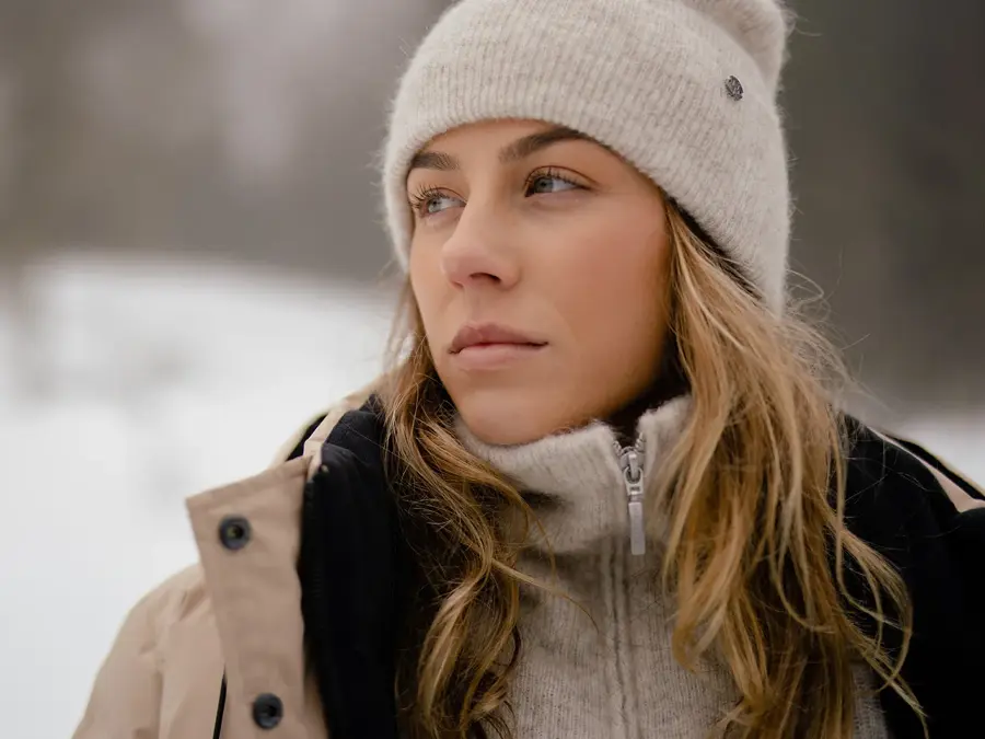 Dame som poserer med beige lue, genser med glidelås og vinterjakke