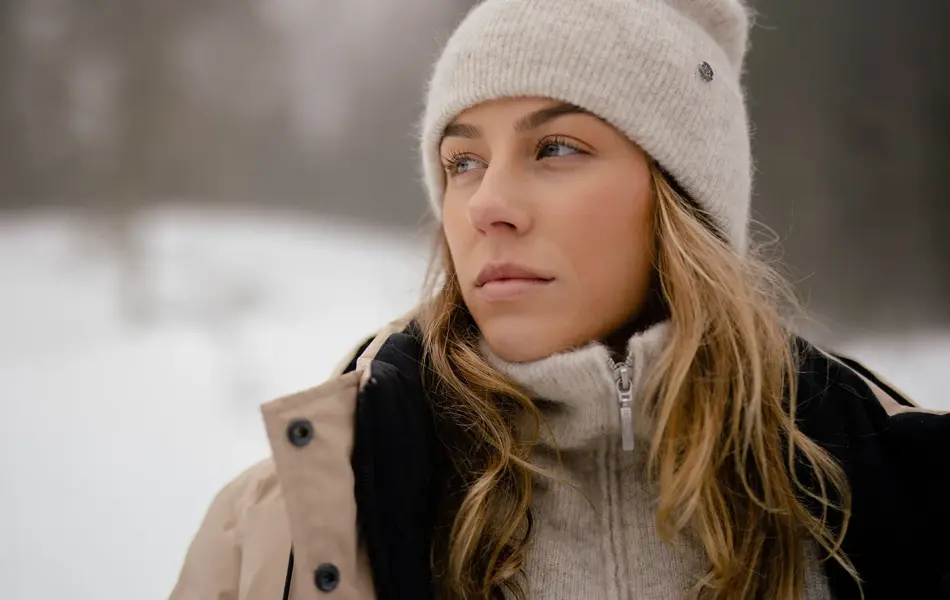 Dame som poserer med beige lue, genser med glidelås og vinterjakke