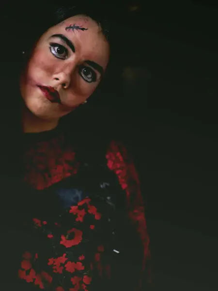 Dame i mørkt rom med skummel sminke